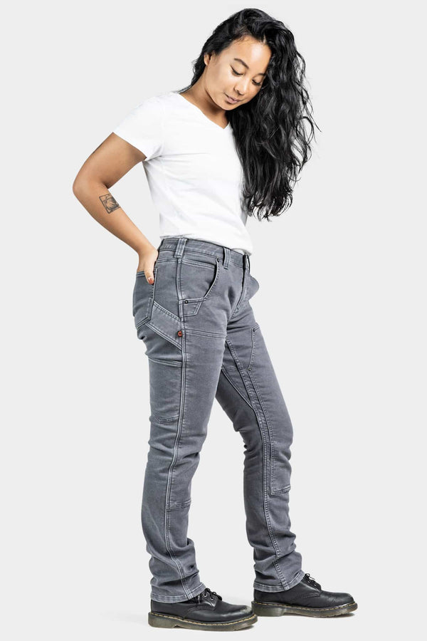 Woman wearing Dovetail Workwear Maven X Slim Pant in Grey Stretch Thermal Denim with white t-shirt, showing the reinforced knee and slim fit design from a side angle