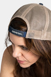 Side view of a woman wearing the Dovetail Embroidered Shop Cap in blue/black denim and khaki, showing the breathable mesh back and adjustable closure strap