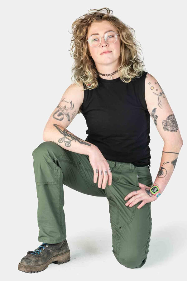 Woman wearing Dovetail Workwear's Britt X Ultralight Work Pant in Lichen Green Ripstop, kneeling to show the tool loops and reinforced knees