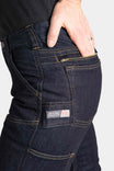 Detail shot of the Dovetail Workwear Britt Utility Pant in FR Denim showing the Hip Slot™ Zip pocket, tool loop, and cargo-style pockets with articulated knee on a woman