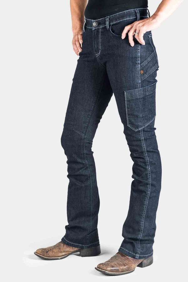 DX Bootcut Pant in CORDURA® Indigo Denim by Dovetail Workwear, shown on a woman wearing brown cowboy boots, featuring visible tool loop and articulated knee seams