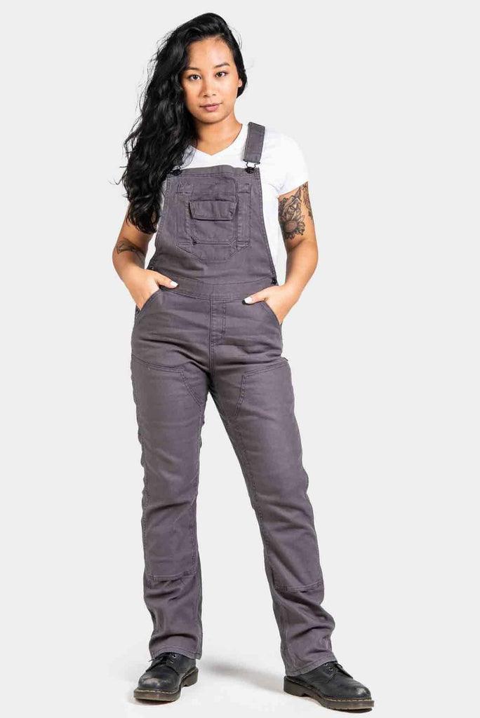 Freshley Overalls For Women in Grey Canvas worn by a woman with hands in pockets, featuring nested pockets and reinforced knees, paired with a white v-neck tee
