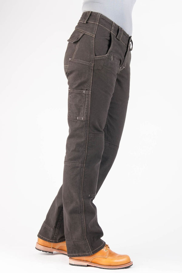 Side view of a woman wearing Dovetail Workwear's Day Construct Pant in Brown Canvas, showcasing multiple pockets, reinforced knees, and relaxed straight-leg fit with work boots