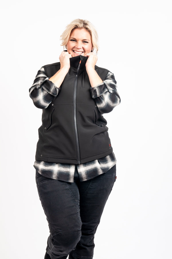Dovetail Workwear M'fon Work Vest in black, worn by a woman with hands near the collar, paired with dark jeans