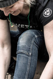 Woman wearing Dovetail Workwear Logo Tee in black, shown from above while looking down at her blue jeans, displaying the classic logo on the chest